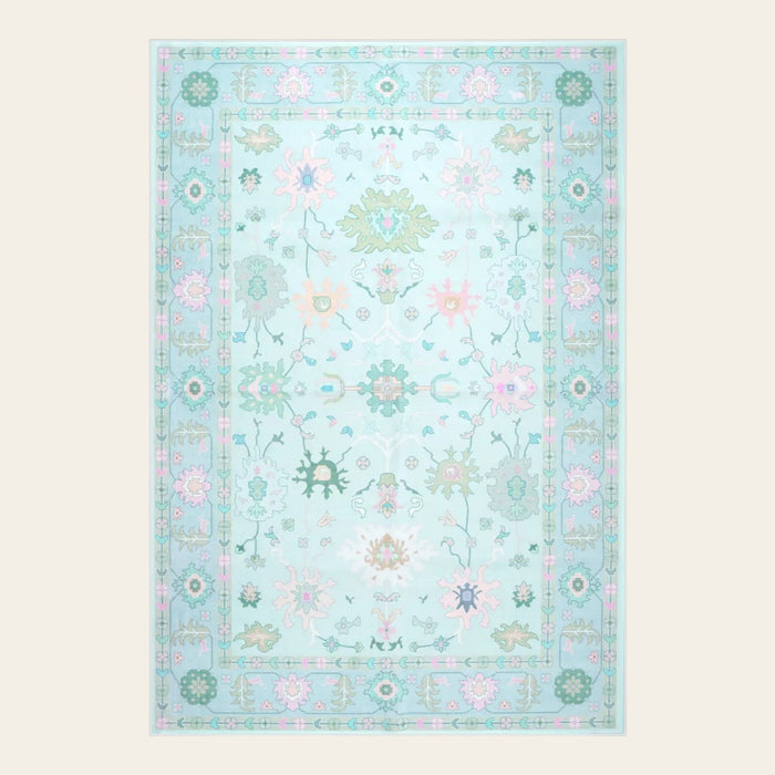 Covaba boho oushak floral area rug in teal haze, shown flat on a plain ivory backdrop