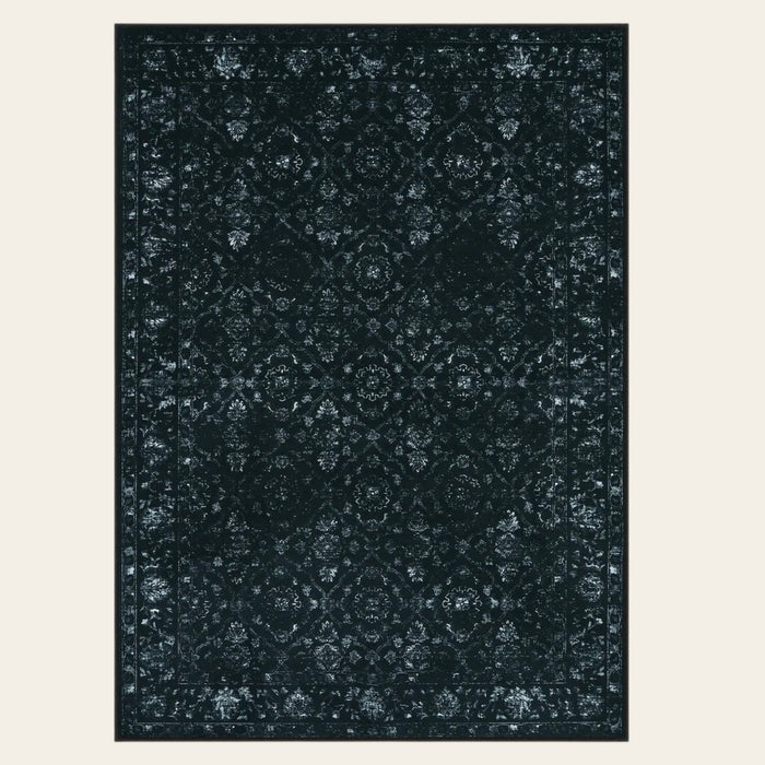 Covaba vintage persian distressed area rug in ink black, shown flat on a plain ivory backdrop