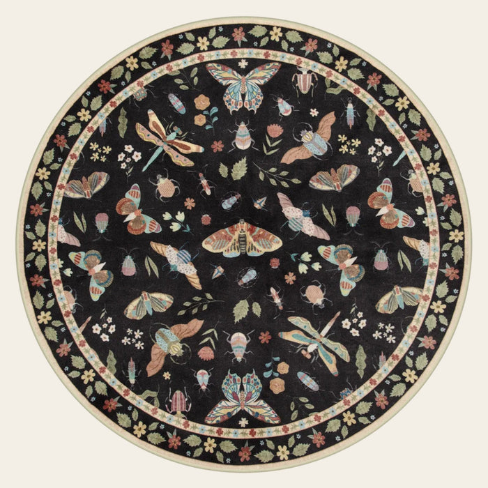 Covaba modern parisian insect round rug in ink black, shown flat on a plain ivory backdrop