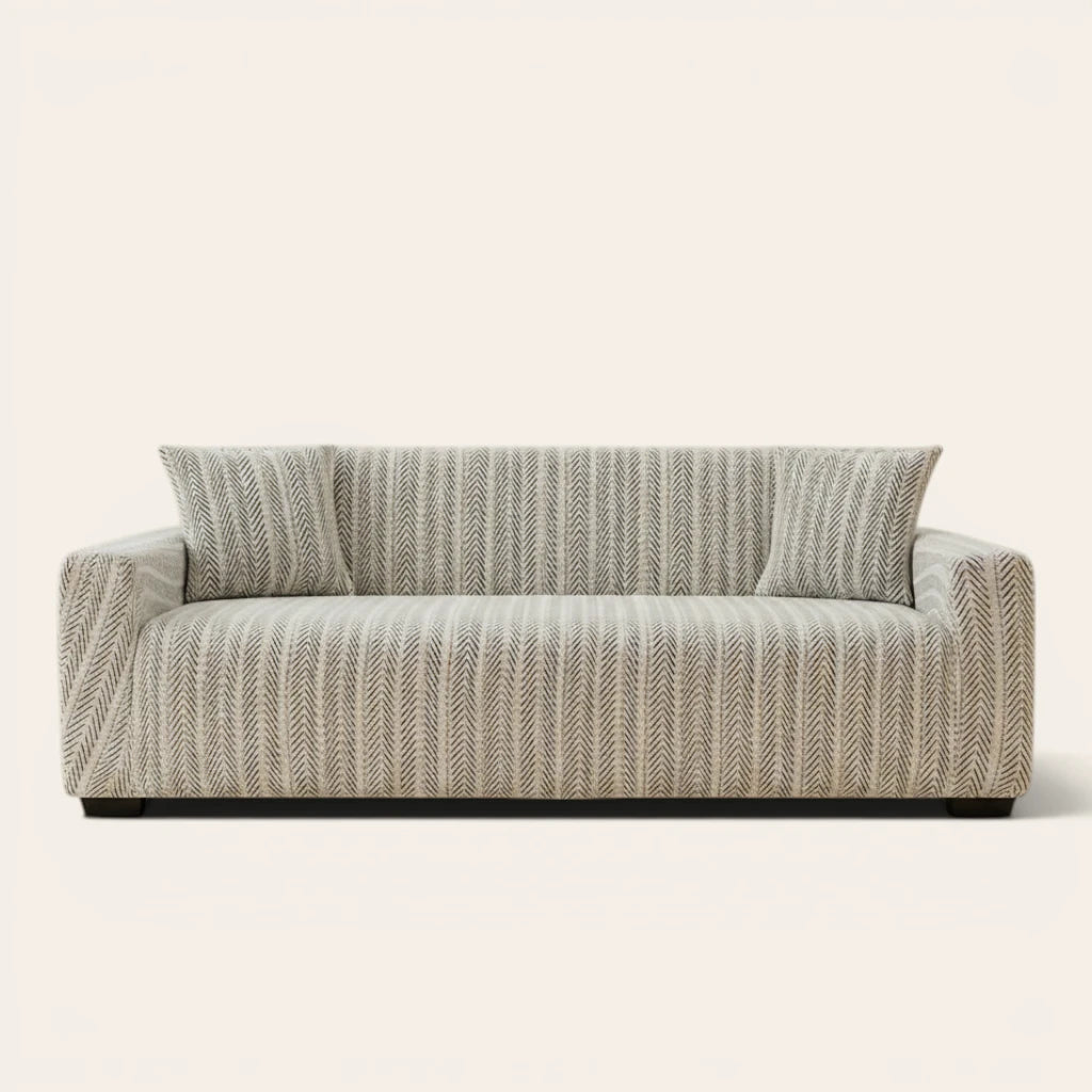 Arrow Gray geometric sofa cover fitted on a three-seat sofa with matching cushions, front view on ivory