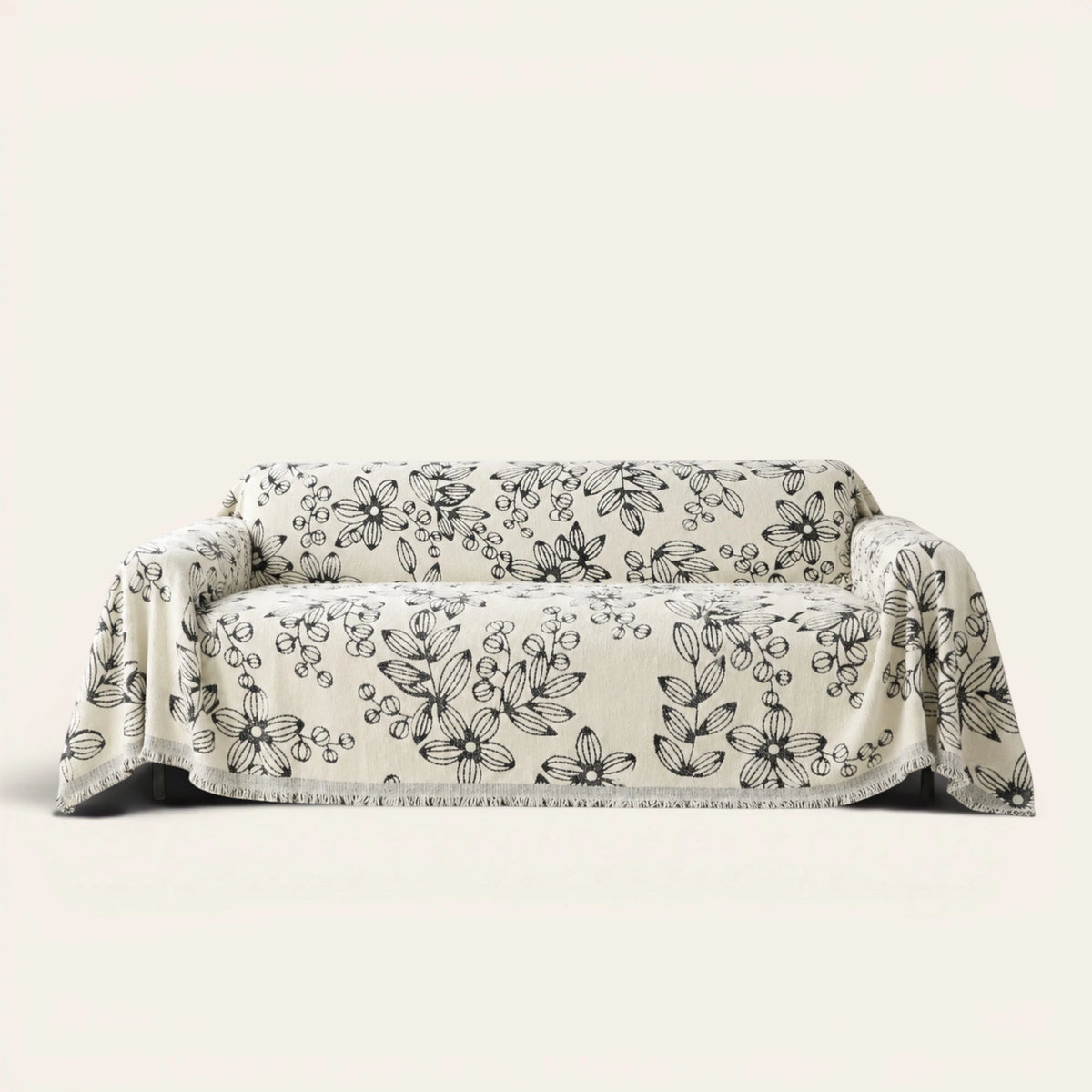Botanic Bliss sofa throw in Botanic Sketch over a couch, front view with sketched black florals and fringe