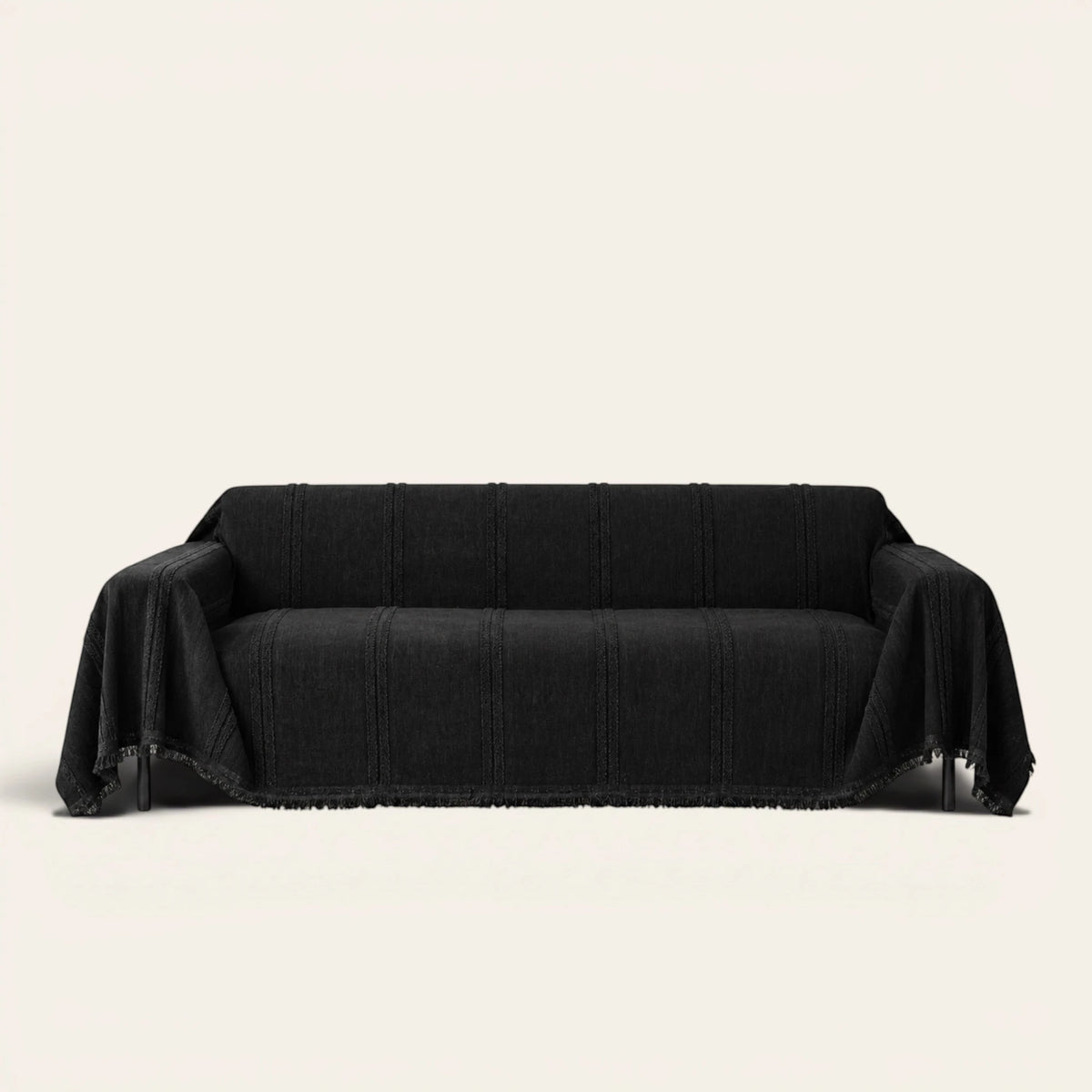 Ebony elegance Classic Striped sofa throw in black, draped over a couch on an ivory backdrop with fringe