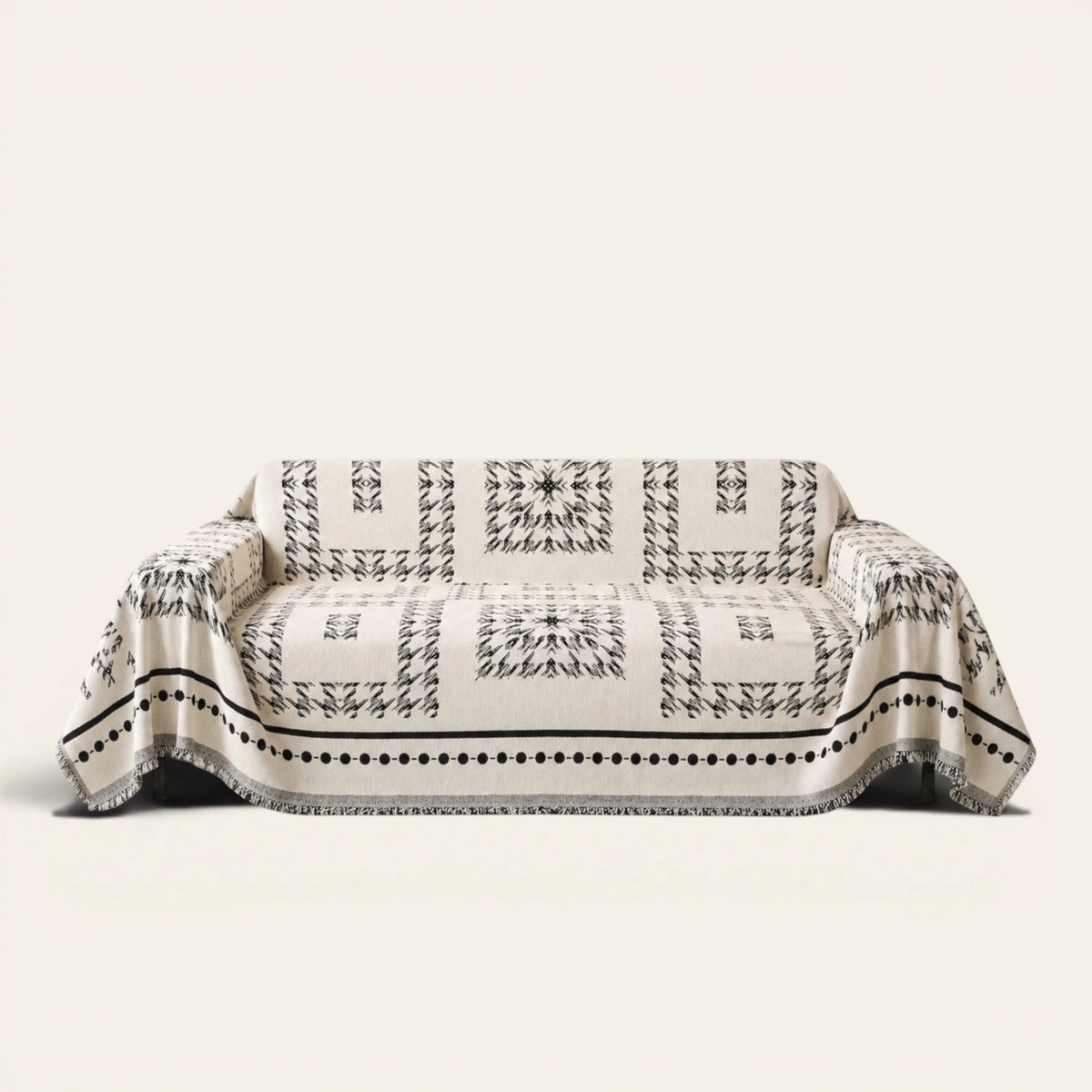 Fringed Boho sofa throw in Ivory Ink draped over a couch, front view on ivory background