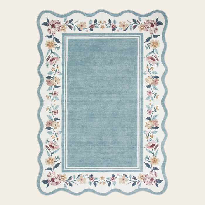 Covaba vintage floral scalloped area rug in dusty blue, shown flat on a plain ivory backdrop