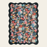 Covaba vintage floral scalloped area rug in ink black, shown flat on a plain ivory backdrop