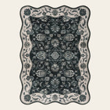 Covaba vintage botanical scalloped area rug in ink black, shown flat on a plain ivory backdrop