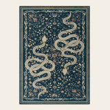 Covaba mystical snake area rug in stormy blue, shown flat on a plain ivory backdrop