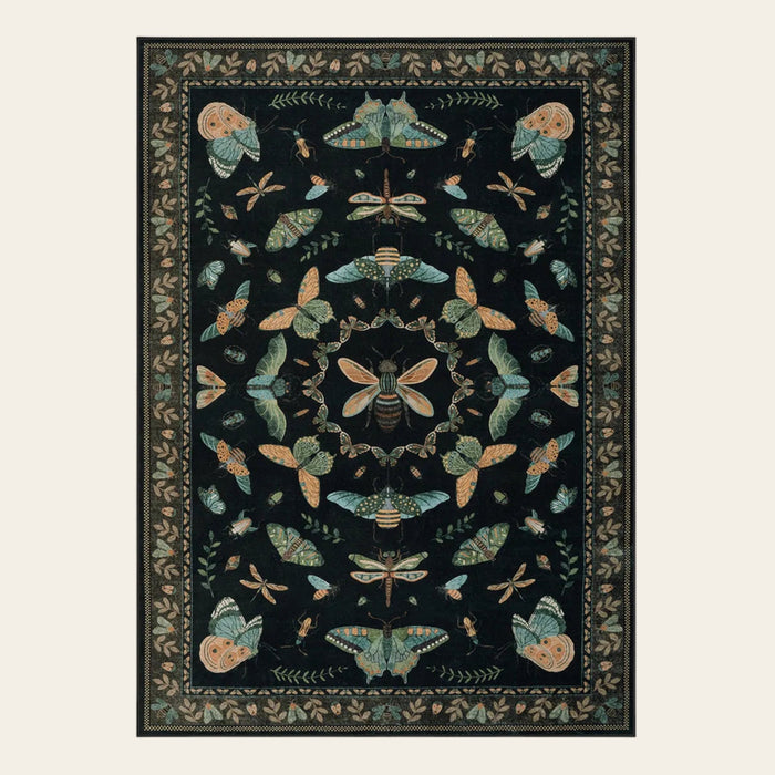Covaba cottagecore botanical insect area rug in ink black, shown flat on a plain ivory backdrop