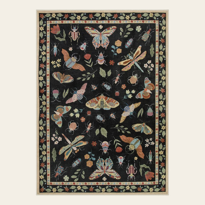 Covaba modern parisian insect area rug in ink black, shown flat on a plain ivory backdrop