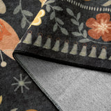 Covaba boho birdsong floral garden rug in ink black, styled in a room setting