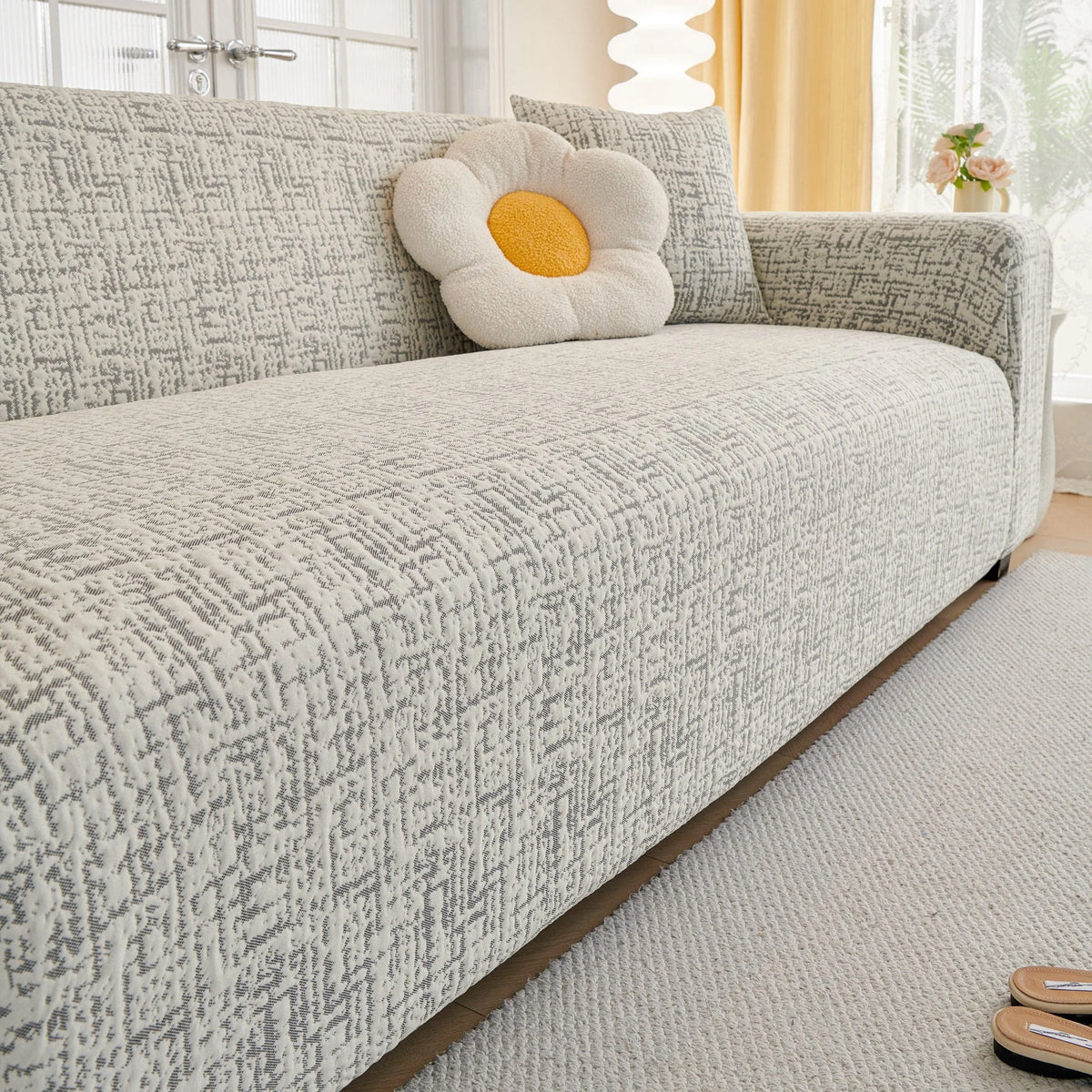 Stone Grey Jacquard sofa cover draped over a three-seater sofa in a bright living room, view 3