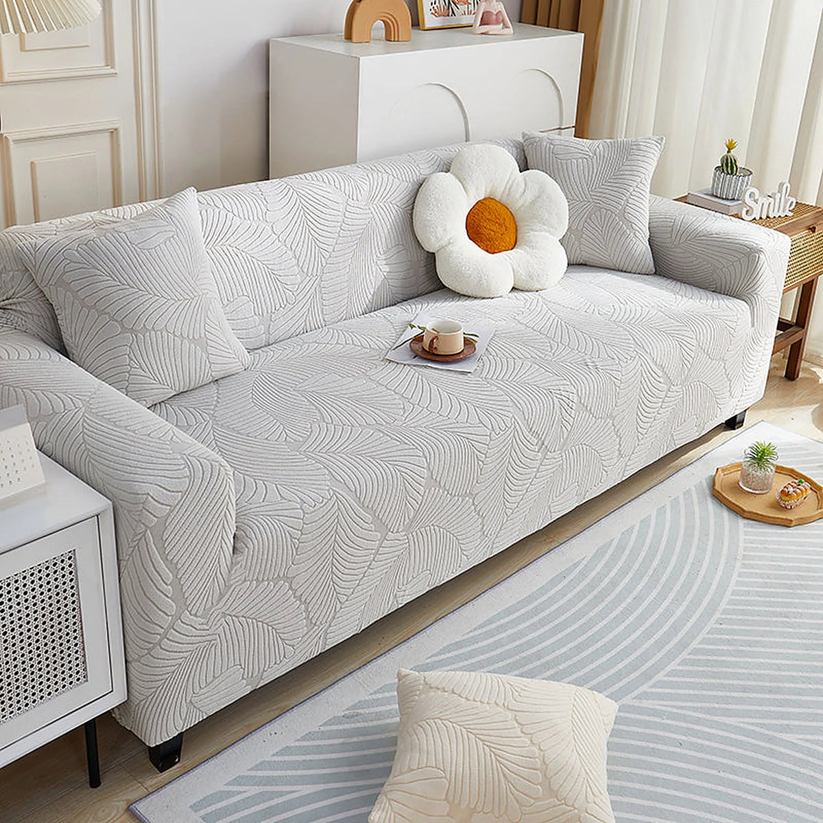 Pearl Grey Palm Relief sofa cover draped over a three-seater sofa in a bright living room, view 2
