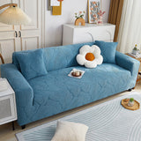 Stormy Blue Palm Relief sofa cover draped over a three-seater sofa in a bright living room