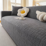 Stone Grey Quilted Waffle sofa cover draped over a three-seater sofa in a bright living room, view 6