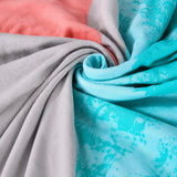 Close-up of the watercolor triangles fabric in sky mist, coral, gray and turquoise swirled to show the soft knit drape