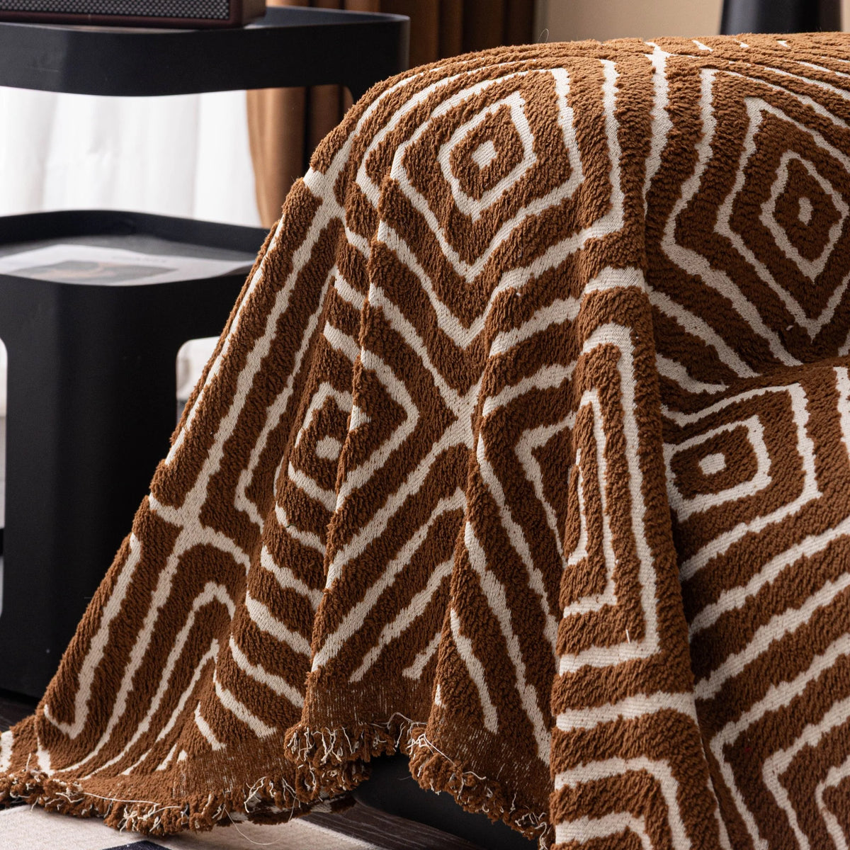 Auburn Brown Geometric Boho sofa throw draped over a three-seater sofa in a bright living room, view 2