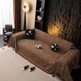 Auburn Brown Geometric Boho sofa throw shown across the seat and backrest of a two-seater, view 2
