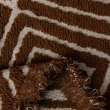 Auburn Brown Geometric Boho sofa throw photographed at an angle beside a floor lamp, view 2