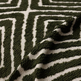 Forest Green Geometric Boho sofa throw photographed at an angle beside a floor lamp, view 4