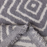 Pearl Grey Geometric Boho sofa throw photographed at an angle beside a floor lamp
