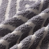 Pearl Grey Geometric Boho sofa throw shown on a straight sofa against a pale wall