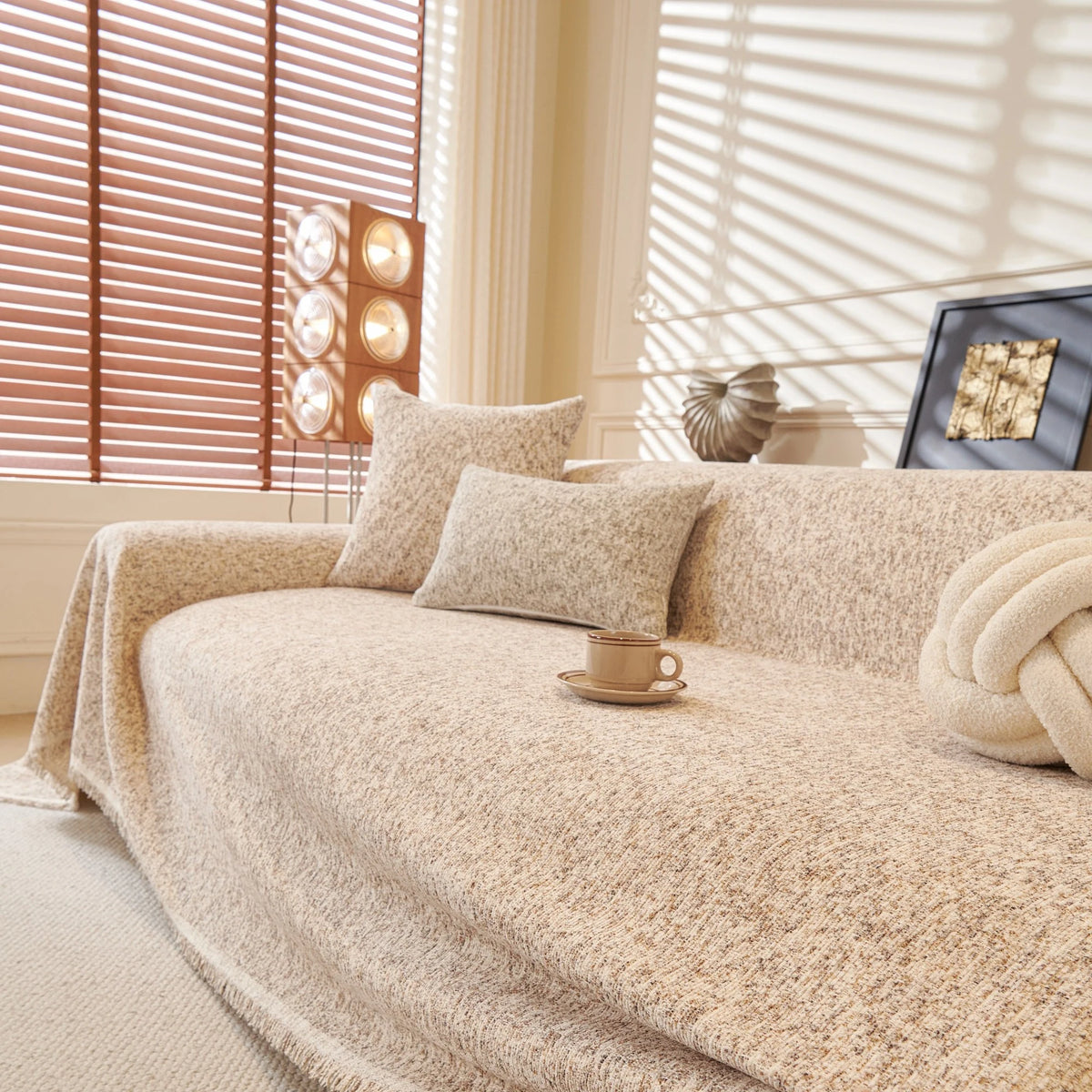 Warm Stone Tweed Knit sofa throw draped over a three-seater sofa in a bright living room, view 2