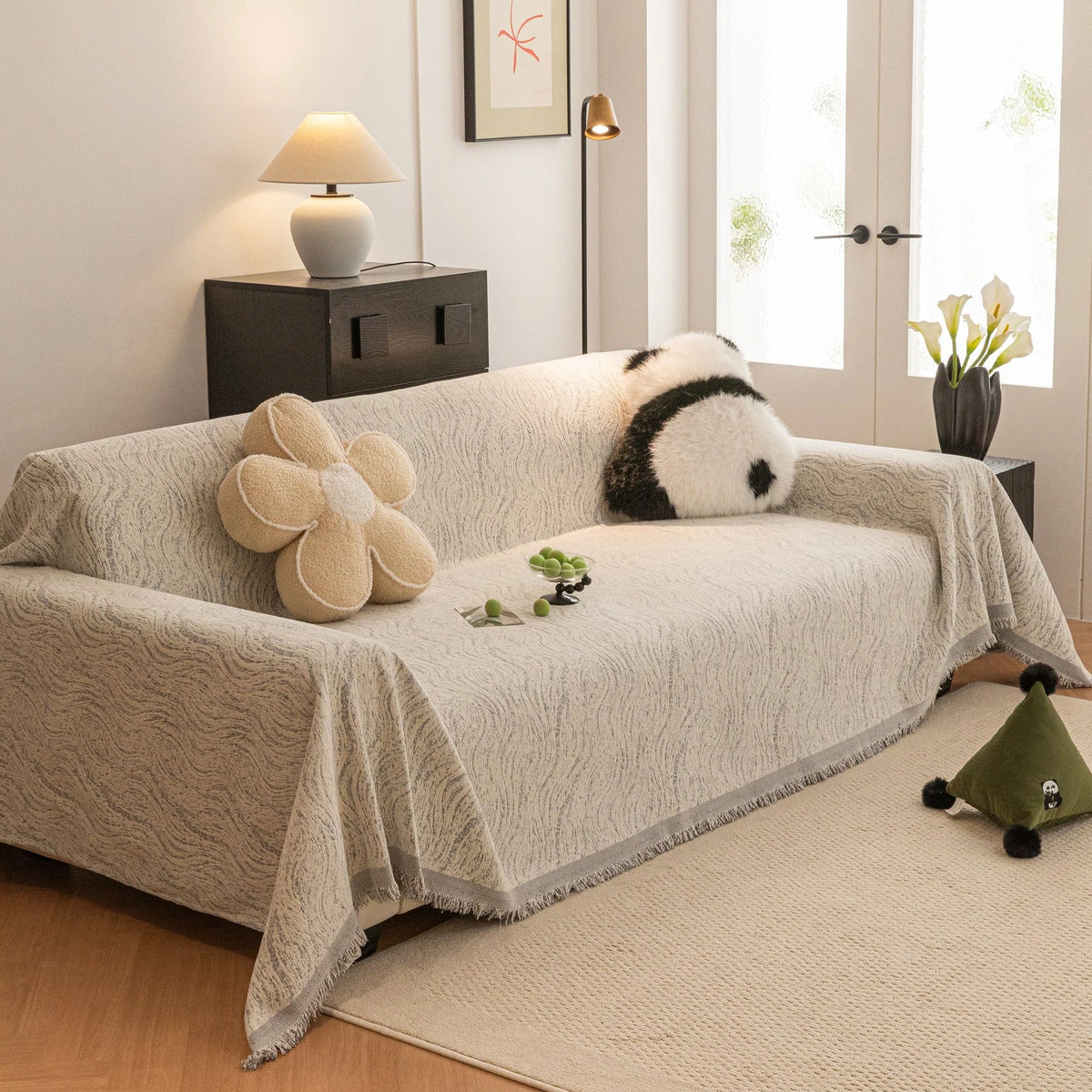 Stone Grey Wave Quilted sofa throw draped over a three-seater sofa in a bright living room, view 3
