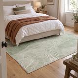 Fern green abstract terrain rug running alongside a bed dressed in white bedding and a terracotta throw