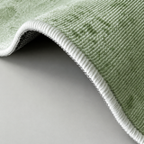 Close-up of the fern green abstract terrain rug folded back to show the textured non-slip backing