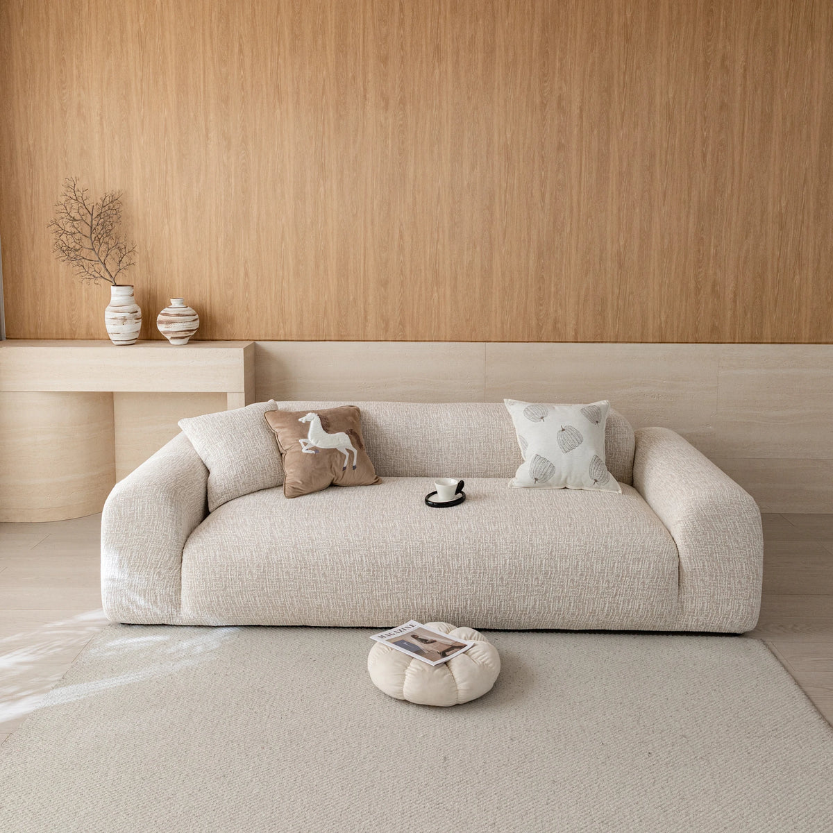 Almond cream chenille sofa cover on a three-seat sofa in a warm wood-paneled living room, front view