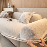 Hands tucking the almond cream chenille cover under the rounded armrest for a snug fit