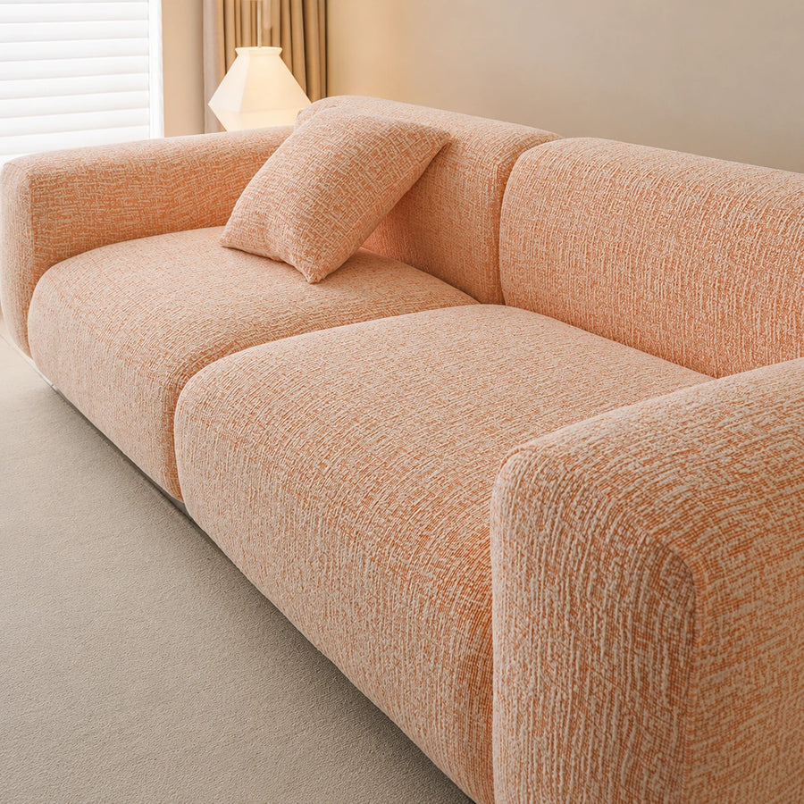 Angled close-up of the peach clay chenille seat and armrest showing the soft woven texture