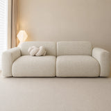 Sage veil chenille sofa cover on a plush sofa, styled with a knot cushion by a window and lamp