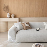 Stone mist chenille sofa cover seen at an angle from the left, styled with printed cushions