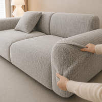 Two hands fitting the stone mist chenille cover over the rounded armrest, showing stretch fit