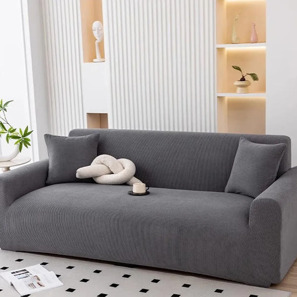 Charcoal gray corduroy sofa cover in a modern living room with fluted wall and knot cushion