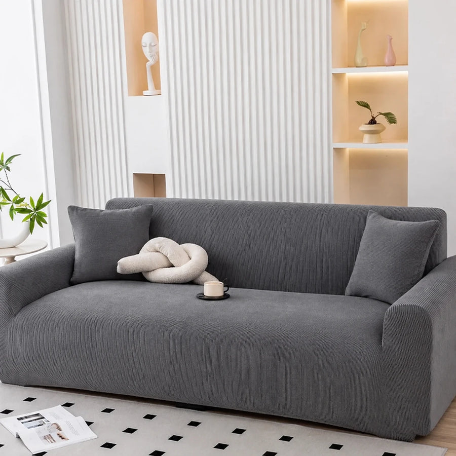 Charcoal gray corduroy sofa cover styled with a knot cushion and coffee cup, front angle