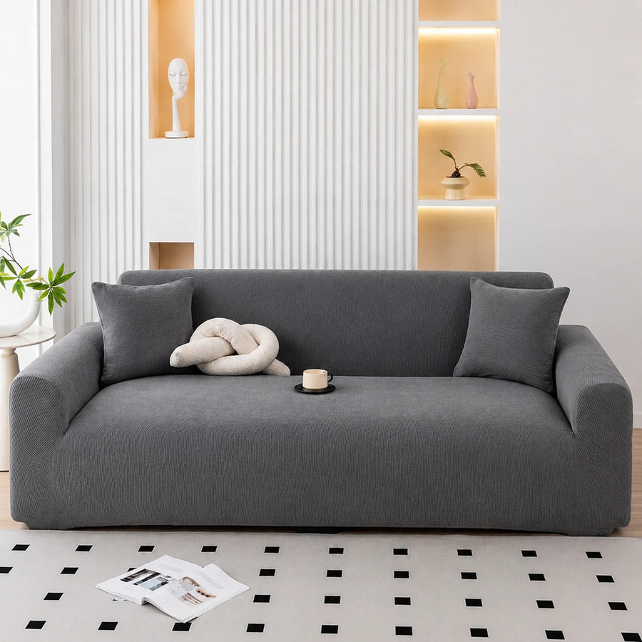 Charcoal gray corduroy sofa cover, wider angle in a bright styled room with cushion and cup