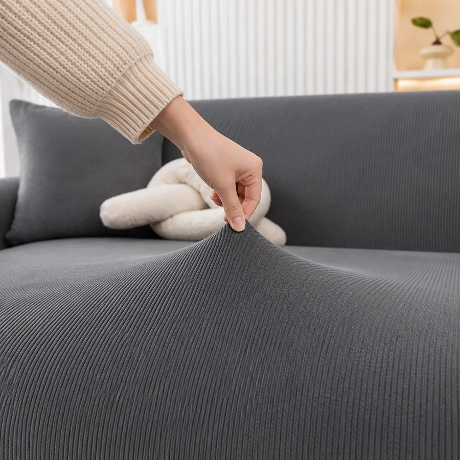 Hand stretching the charcoal gray corduroy cover, showing its ribbed weave and stretch