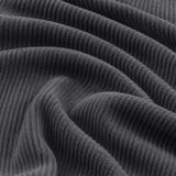 Macro of charcoal gray corduroy fabric in soft folds revealing the ribbed knit texture