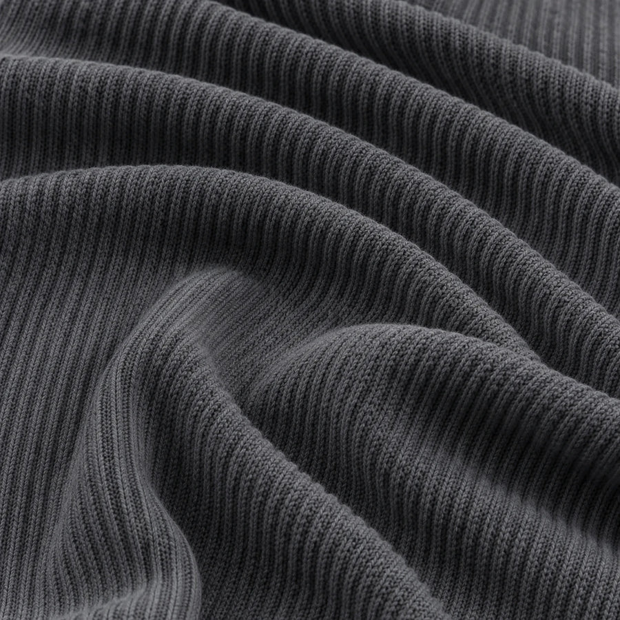 Macro of charcoal gray corduroy fabric in soft folds revealing the ribbed knit texture