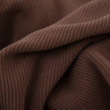 Macro of cocoa brown corduroy fabric folds revealing the soft ribbed knit texture
