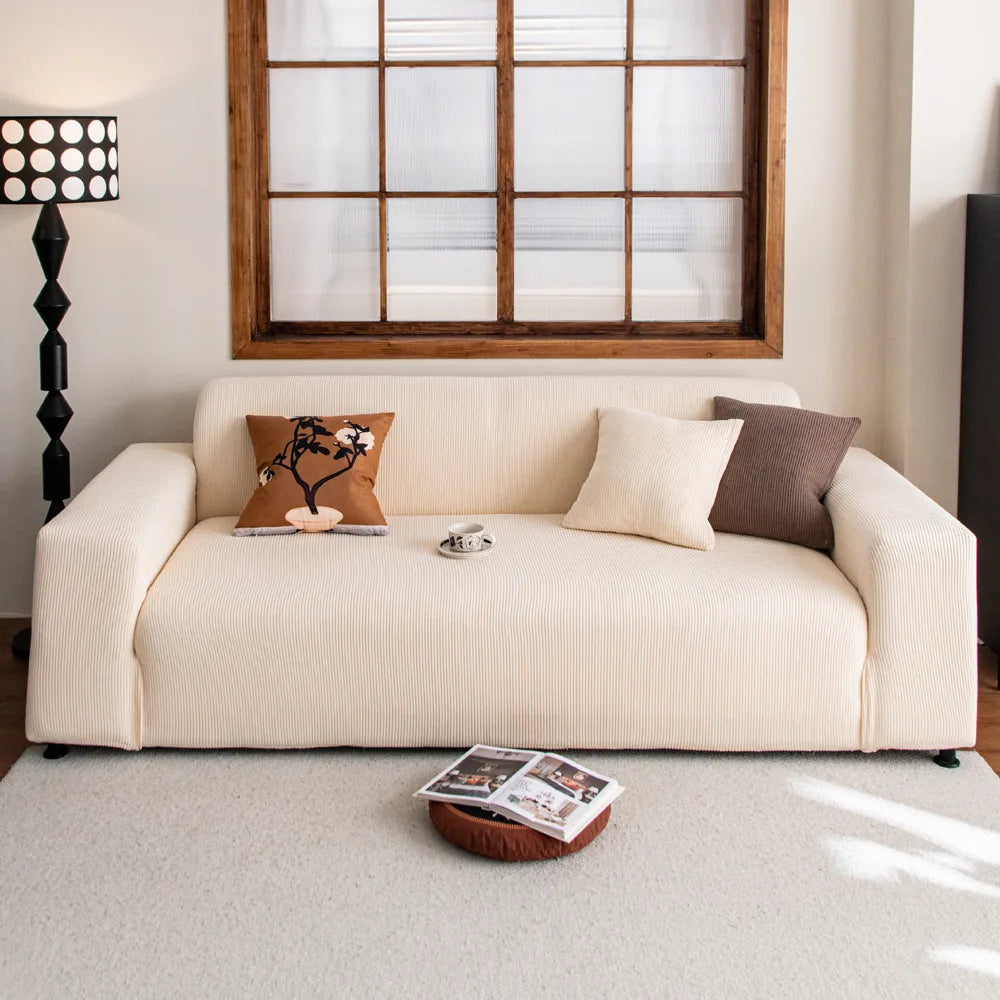 Cream corduroy sofa cover styled in a bright living room with terracotta and brown cushions