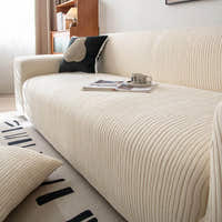 Angled view of cream whisper corduroy sofa cover with an open book and cup on the seat