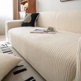 Angled view of cream whisper corduroy sofa cover with an open book and cup on the seat