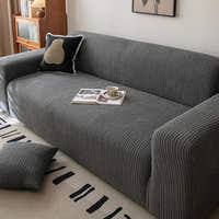 Graphite shadow corduroy sofa cover with an open magazine and cushion in a cozy lounge