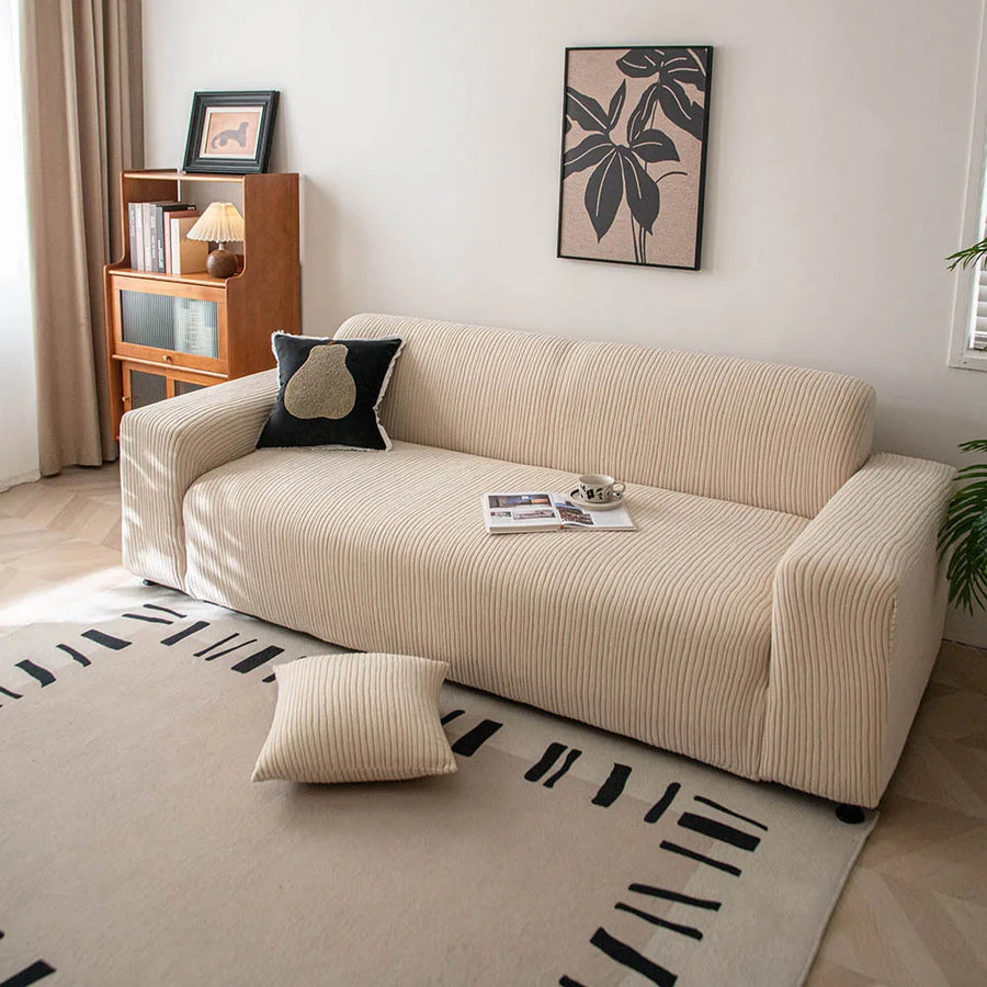 Linen beige corduroy sofa cover styled in a sunlit room with a cushion and patterned rug