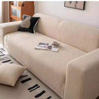 Angled view of linen beige corduroy sofa cover with a black cushion and coffee cup