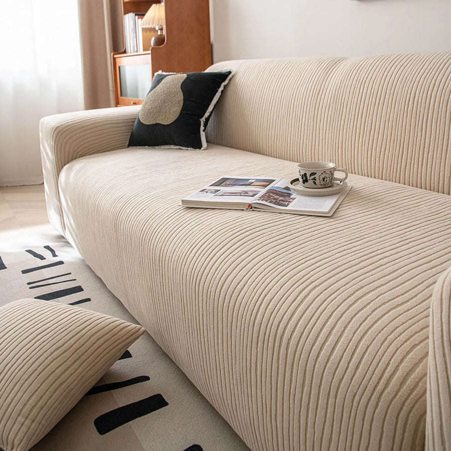 Close up angle of linen beige corduroy sofa cover with an open book and cup on the seat