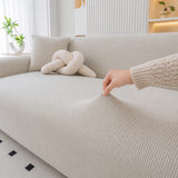 Hand pulling the stretchy mist gray corduroy cover to show its flexible ribbed fabric